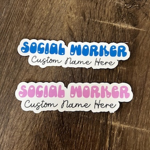May include: Two stickers with the text "Social Worker" in a bubble font with hearts. The top sticker is blue with white hearts and the bottom sticker is pink with white hearts. Both stickers have the text "Custom Name Here" in black cursive writing.