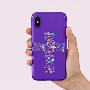May include: A purple phone case with a floral cross design. The cross is made up of colorful flowers and leaves.