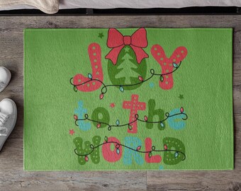 Könnte beinhalten: Grüne Fußmatte mit den Worten "Joy to the World" in roten, blauen und grünen Buchstaben mit einem Weihnachtsbaum und Lichtern.