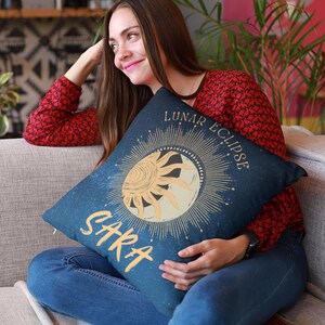 May include: A blue throw pillow with a gold sun and moon design and the text "Lunar Eclipse" and "Sara".