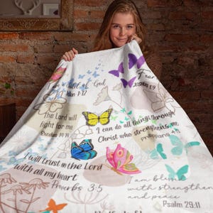 May include: White fleece blanket featuring a colourful butterfly design and inspirational bible verses. The verses include "I am a child of God", "The Lord will fight for me", "I can do all things through Christ who strengthens me", "I will trust in the Lord with all my heart", and "I am blessed with strength and peace".