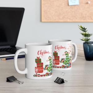 May include: Two white ceramic mugs with a Christmas theme. The mugs feature a design of elves carrying presents on a train. The text "Christmas" is written on both mugs.