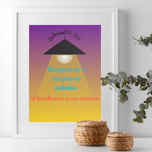 May include: A framed print with a purple, orange, and yellow gradient background. The print shows a black lamp illustration with the text "Salmos 119-105" and a Spanish quote. Two woven baskets with lids are in the foreground.