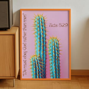 May include: A framed art print featuring three blue cacti with yellow spines against a pink background. The print includes the text "We must obey God rather than men" and "Acts 5:29" in a brown font. The frame is orange.