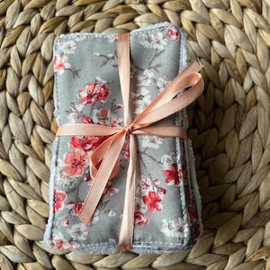 Peut inclure: Un lot de disques démaquillants réutilisables avec un imprimé floral dans les tons gris, rose et blanc. Les disques sont liés ensemble par un ruban de couleur pêche.