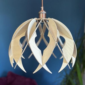 Pode incluir: Uma luminária pendente de madeira com um design geométrico. A luminária é feita de madeira clara e tem um acabamento em cobre. A luminária está pendurada no teto.