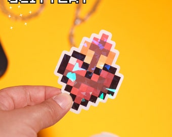 May include: A holographic sticker of a red and orange pixelated heart. The sticker is on a yellow background.