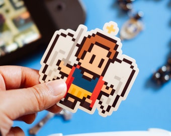May include: A pixel art sticker of a cartoon angel with a halo and wings. The angel is wearing a red and blue tunic with a yellow sash. The sticker is on a blue background.