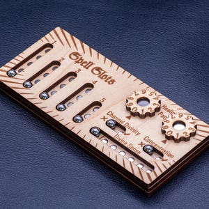 May include: A rectangular light-coloured wooden game tracker featuring the text Spell Slots, with five vertical tracks containing small metal ball bearings. It includes two circular rotating dials, and horizontal tracks labelled Channel Divinity, Divine Sense, Healing Pool, and Concentration.