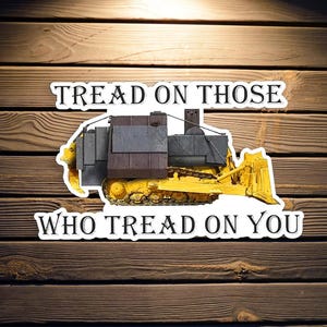 May include: A yellow bulldozer with a black armored cab, with the text "Tread on those who tread on you" on a white background.
