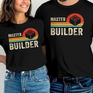 Peut inclure: Deux t-shirts noirs avec un design rétro représentant une brique Lego et le texte "Master Builder".