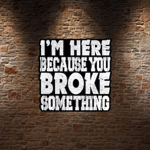 May include: A square black sign with white distressed lettering that reads I'M HERE BECAUSE YOU BROKE SOMETHING. The text is arranged in four lines with a bold, blocky font style, featuring a weathered texture on the white letters against the black background.