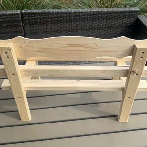 Puede incluir: Un peque&ntilde;o banco de madera sin terminar con un respaldo decorativo festoneado. El banco est&aacute; construido con madera de color claro y presenta un dise&ntilde;o simple y robusto con uniones visibles. Ideal para uso en interiores o exteriores.