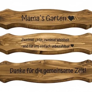 Puede incluir: Tres letreros de madera con un dise&ntilde;o ondulado y tinte marr&oacute;n oscuro. El letrero superior dice "Mama's Garten" con un coraz&oacute;n. El letrero del medio dice "Zweimal Liebe, zweimal Weisheit - und f&uuml;r uns einfach unbezahlbar." El inferior dice "Danke f&uuml;r die gemeinsame Zeit!"