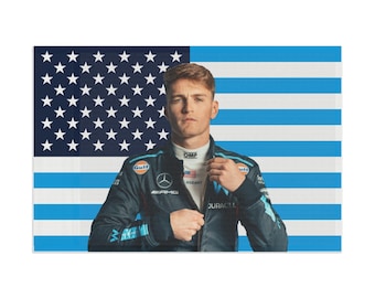 May include: A man wearing a blue and white racing jacket with the logos "Gulf", "OMP", "AMG", "ROGAN", and "DURACELL" stands in front of an American flag.
