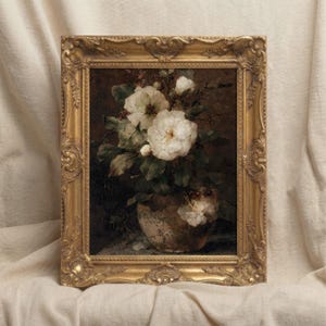 May include: A framed floral still life painting. The artwork features white roses in a vase, set against a dark background. The ornate gold frame adds a vintage aesthetic to the piece.