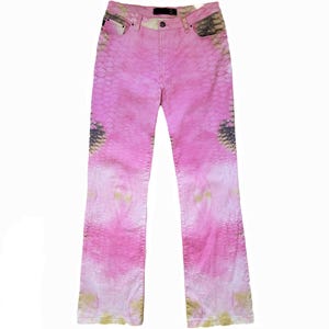 May include: Pink jeans featuring a subtle snakeskin pattern throughout the fabric. These trousers include a standard button closure, a zip fly, and five pockets, with darker grey scale detailing visible on the front hip and thigh areas.