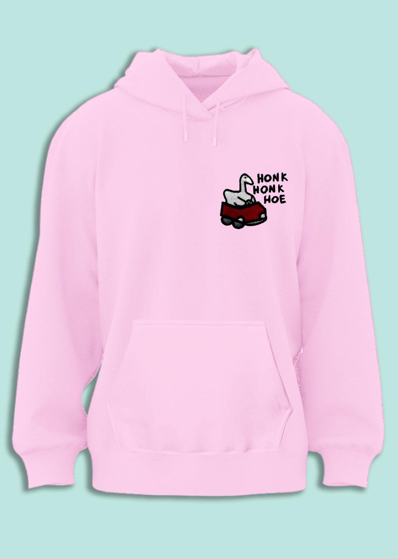 A pink hoodie with a cartoon image of a goose in a car and the text "honk honk hoe" printed on it.