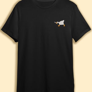 May include: A black t-shirt with a white embroidered image of a goose holding a knife.