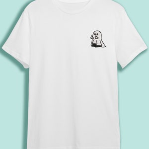 May include: White t-shirt with a black outline of a ghost giving the middle finger.