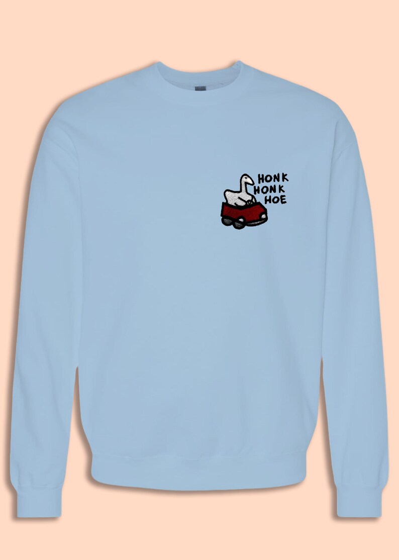 A light blue sweatshirt with a cartoon image of a car and the text "HONK HONK HOE" printed on the front.