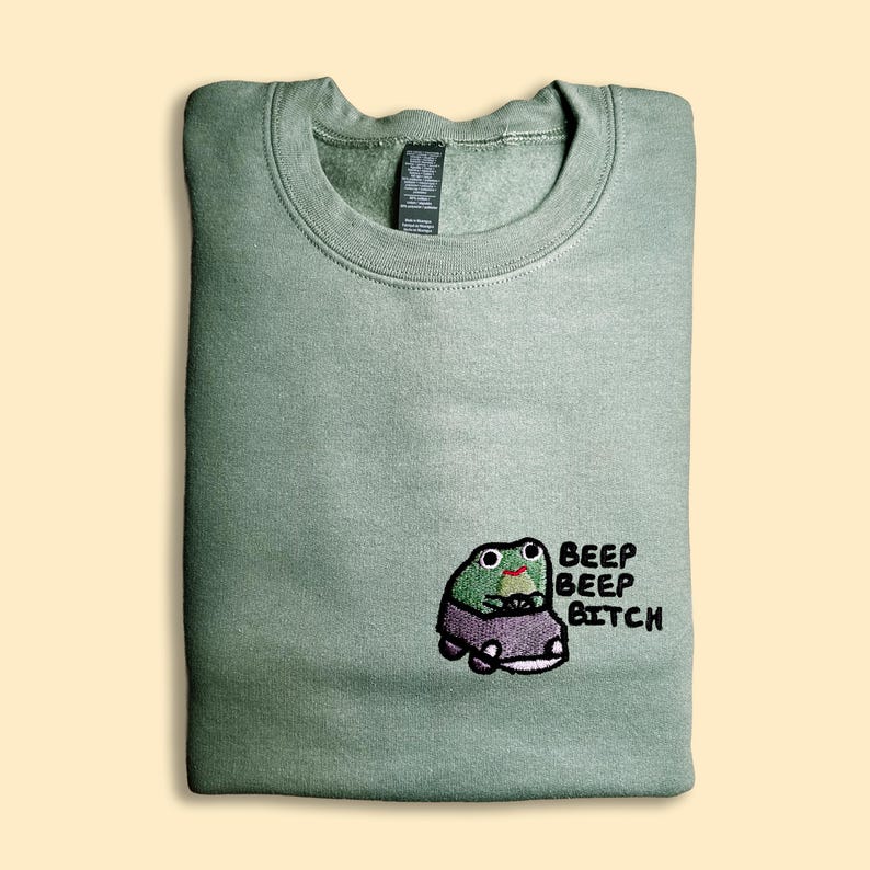A green sweatshirt with a cartoon frog and the text "BEEP BEP BITCH" printed on it.