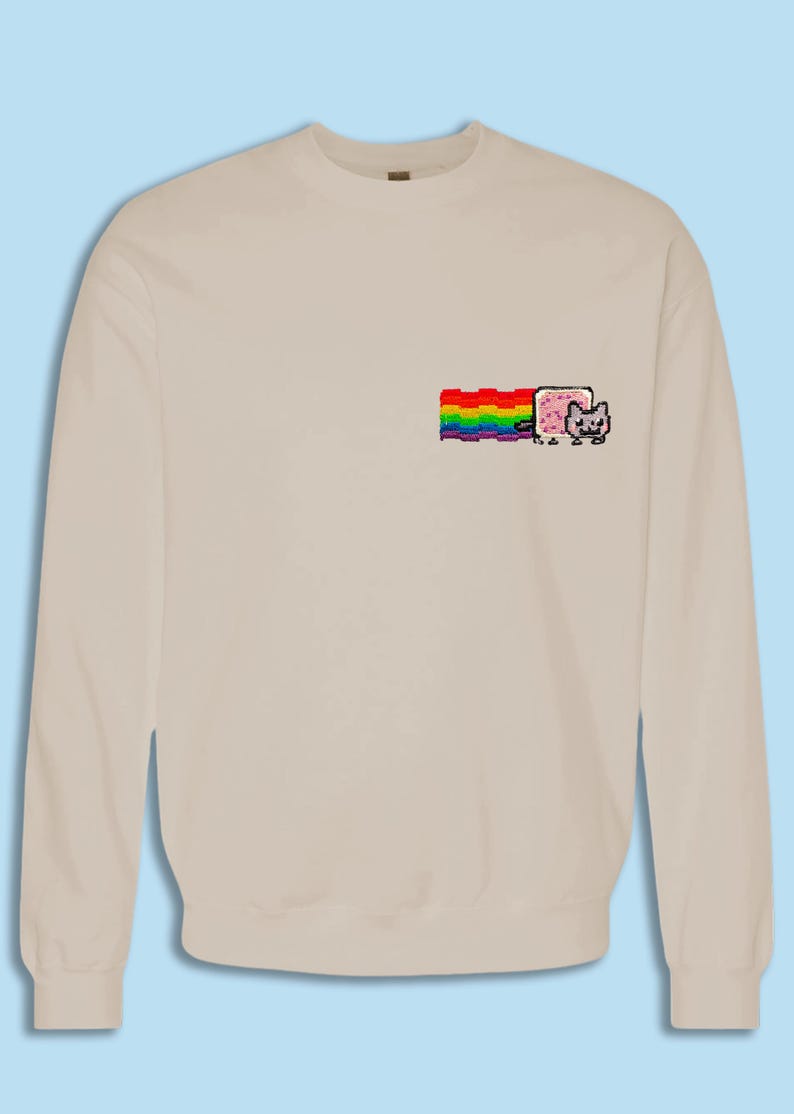 A beige sweater with a colorful graphic design on the front, depicting a cat with a rainbow-colored stripe.