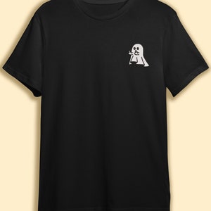 May include: A black t-shirt with a white ghost design. The ghost is making a rude gesture with its hand.