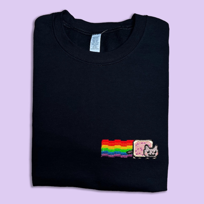 A black t-shirt with a colorful pixel art design of a cat and a rainbow on the front.