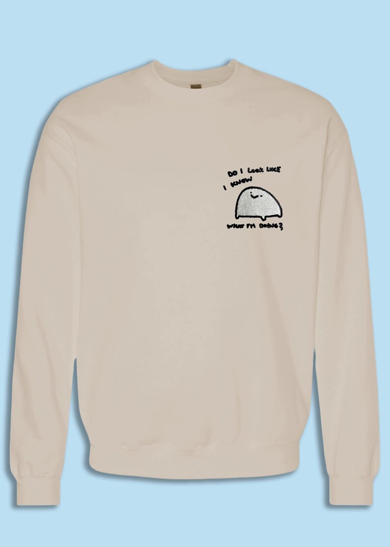 A beige sweater with a small cartoon character on the front.