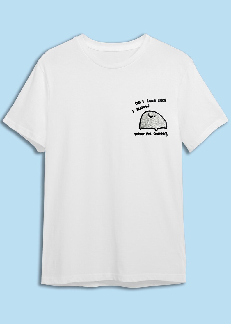 A white t-shirt with a small cartoon character and text printed on it.