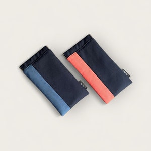 May include: Two rectangular fabric cases with contrasting colored panels. One case is navy blue with a light blue panel and the other is navy blue with a coral panel. Both cases have the word "VIVID" printed on them.