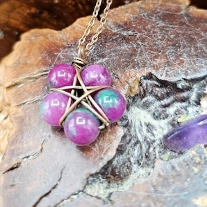May include: A copper wire wrapped pendant featuring a star shape with six pink and green gemstone beads.