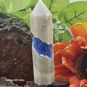 May include: A white crystal point with a blue crystal inclusion. The crystal is about 4 inches tall and has a hexagonal shape.