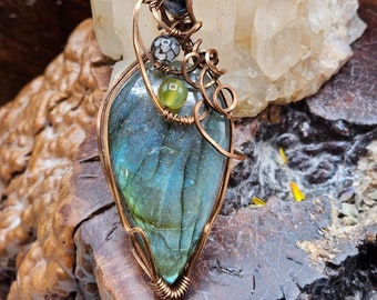 Peut inclure: Un pendentif en fil de cuivre enroulé avec une pierre précieuse de labradorite bleue en forme de larme avec des accents d'agate verte et noire.