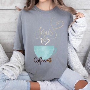 May include: A gray t-shirt with the text "Jesus & Coffee" in black and gold lettering. A blue coffee cup with steam rising from it is above the text. A gold heart with a cross inside is above the text "Jesus".