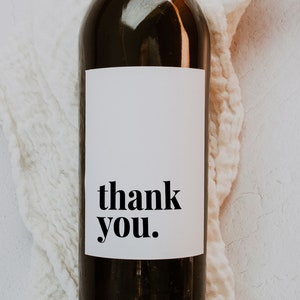 Könnte beinhalten: Eine schwarze Weinflasche mit einem weißen Etikett, auf dem "thank you" steht.