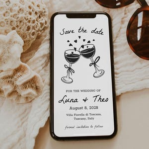 Pode incluir: Um cartão de guardar a data com uma ilustração em preto e branco de duas taças de vinho brindando. O texto diz "Save the date" e "For the wedding of Luna & Theo" com a data "August 8, 2028" e a localização "Villa Fiorella di Toscana, Tuscany, Italy". O texto "formal invitation to follow" está na parte inferior do cartão.
