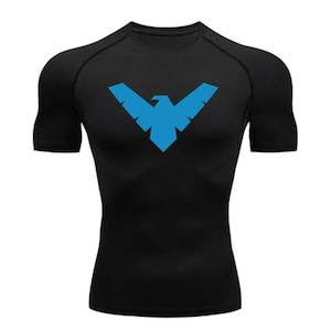 Peut inclure: T-shirt de compression noir avec un logo d'oiseau bleu sur la poitrine. Le t-shirt à manches courtes est conçu pour le sport et a une coupe ajustée. Le logo est un dessin géométrique d'un oiseau aux ailes déployées.