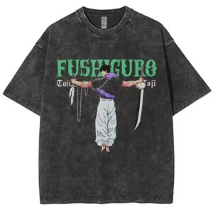 May include: Dark gray t-shirt with a graphic of a character from an anime series. The character is depicted with a sword and chains, and the shirt features the name "Fushiguro" in green lettering. The shirt has a vintage, worn look.