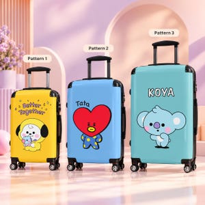 May include: Three upright rolling suitcases with telescoping handles and four wheels. The yellow suitcase features a character and the text Better Together. The blue suitcase shows a red heart character labelled Tata. The teal suitcase features Koya.