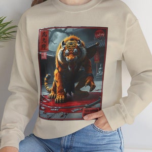 May include: A beige sweatshirt with a graphic print of a tiger in a red frame. The tiger is snarling and has a red background. The text "虎" is printed in red on the frame.