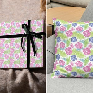 Puede incluir: Un papel de regalo con estampado floral rosa y verde con una cinta negra. El mismo patr&oacute;n tambi&eacute;n est&aacute; en una almohada.