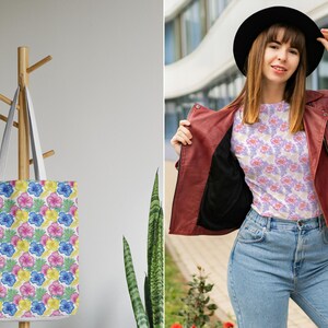 Puede incluir: Una bolsa de tela blanca con un estampado floral de flores rosas, amarillas y azules. La bolsa tiene una base de lona blanca y correas blancas.