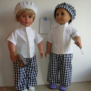 Könnte beinhalten: Zwei Puppen, die als Köche verkleidet sind, tragen weiße Kochjacken mit schwarzen Knöpfen, schwarz-weiß karierte Hosen und weiße Kochmützen. Eine Puppe hält eine Reibe, die andere einen Schneebesen.