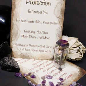 May include: A Protection Spell Jar with a purple wax seal, amethyst crystals, black tourmaline, and a sage bundle are arranged in a still life. A card with the word "Protection" and instructions is also present.