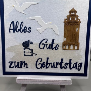 Grußkarte 3D schlicht weiß blau handgemacht. Maritimes Motiv Leuchtturm an der Küste, Möwen Strandkorb, Schriftzug: zum Geburtstag