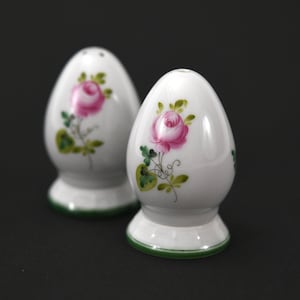 May include: A pair of white ceramic salt and pepper shakers with green trim and pink rose floral designs.