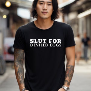 May include: A black t-shirt with white text that reads "Slut for Deviled Eggs".