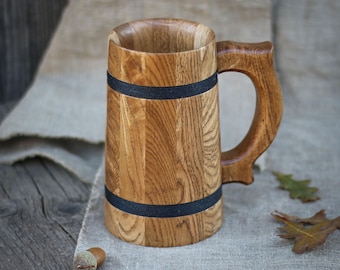 May include: A wooden beer stein with a dark brown finish and black bands around the middle. The stein has a large handle and is made of natural wood.